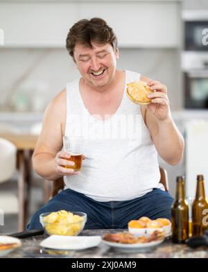 Man drinks beer and eats a hamburger Stock Photo