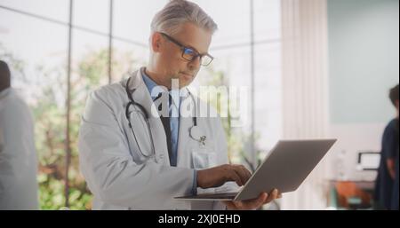Portrait of a Medical Health Care Professional Using a Laptop Computer in Hospital Office. Clinic Physician in White Coat Appointing Prescriptions Online, Updating Electronic Health Records Stock Photo