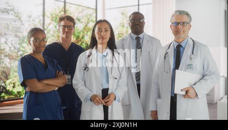 Team Portrait of a Female and Male Successful Diverse Medical Healthcare Professionals Standing as a Group in a Modern Hospital Office, Posing, Looking at Camera and Smiling Stock Photo