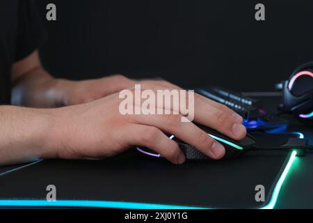 Gamer using modern wired computer mouse at black table, closeup Stock Photo