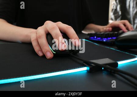 Gamer using modern wired computer mouse at dark table, closeup Stock Photo
