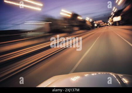 Night drive. Driving a car on highway at night. POV view - silver car bonnet and empty road ahead. Long exposure image of driving car at speed. Stock Photo