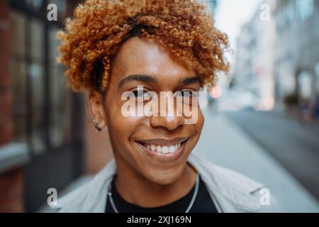 A young man with curly hair is smiling for the camera Stock Photo