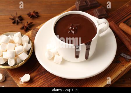 Tasty melted chocolate in cup and marshmallows on wooden table, closeup Stock Photo