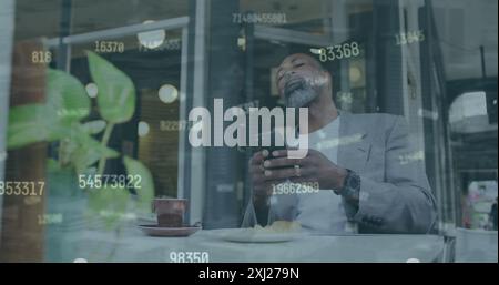 Image of changing numbers over senior african american man using phone in cafes. Digital composite, multiple exposure, business, growth, beverages, re Stock Photo