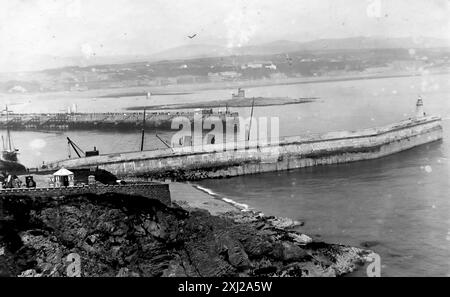 The breakwater and pier, Douglas, Isle of Man. Viewed from high ground. This photograph is from an Edwardian original, around 1910. The original was part of an album of150 albumen photographs, of variable quality, many of which I have photographed. The collection included images particularly from the Isle of Man and the English county, Devonshire. Annotations were included in the album but, unfortunately, there were no specific dates. Original photos were, on average 6x4 ½ inches. Stock Photo