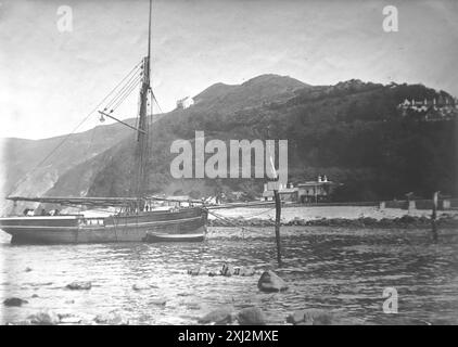 The mouth of the Lyn River with a boat on the water and distant cliffs. Lynmouth, Devon. This photograph is from an Edwardian original, around 1910. The original was part of an album of150 albumen photographs, of variable quality, many of which I have photographed. The collection included images particularly from the Isle of Man and the English county, Devonshire. Annotations were included in the album but, unfortunately, there were no specific dates. Original photos were on average 6x4 ½ inches. Stock Photo