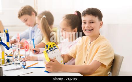 Happy Boy Building Robot in Elementary School Classroom Stock Photo