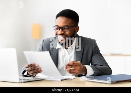 Cheerful black businessman checking reports and making notes Stock Photo