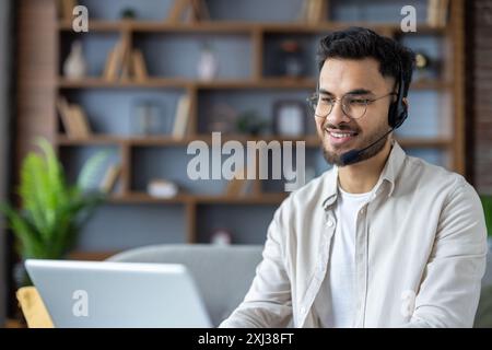 Smiling customer service representative working remotely from home office with headset and laptop. Professional support agent providing customer care while maintaining a positive , friendly attitude Stock Photo