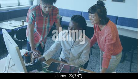 Asian intern, biracial intern, and African American colleague review photos together. They are focusing on details displayed on computer screen and pr Stock Photo