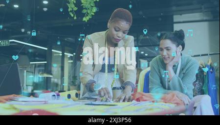 Image of multiple icons connected with lines over diverse fashion designers discussing ideas. Digital composite, multiple exposure, creativity, teamwo Stock Photo