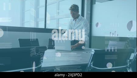Image of statistical data processing against thoughtful caucasian man using laptop at office. Computer interface and business data technology concept Stock Photo