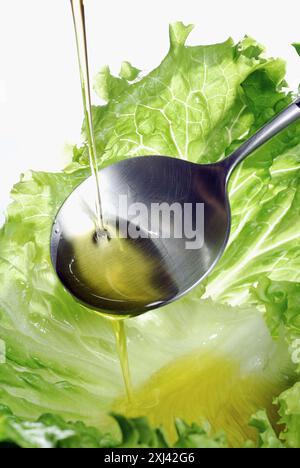 Pouring a drop of olive oil onto a lettuce leaf Stock Photo