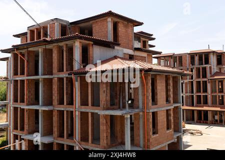 Cottage, Building Under Construction, Made Of Red Hollow Clay Bricks, Tile Roof, Balcony. Blue Sky And Green Tree On Background. Village, Town house Stock Photo