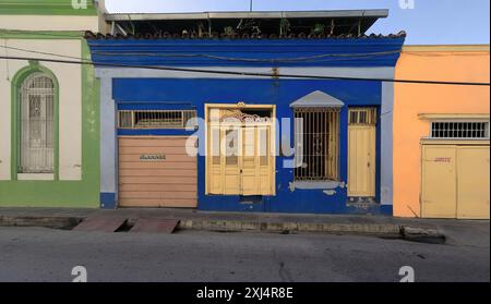 515 One-storey Colonial townhouses of green-white-light blue-azure blue-orange facades, wood doors and grille windows on Heredia Street. Santiago-Cuba Stock Photo