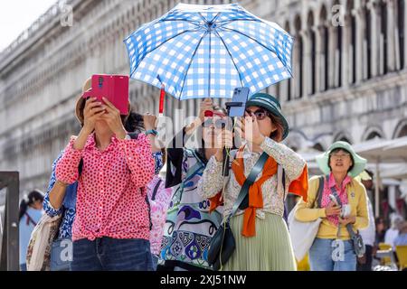 Tourists from Asia with mobile phones and parasols taking photos. Souvenir photo of St Mark's Square, Venice, Venice, Italy Stock Photo