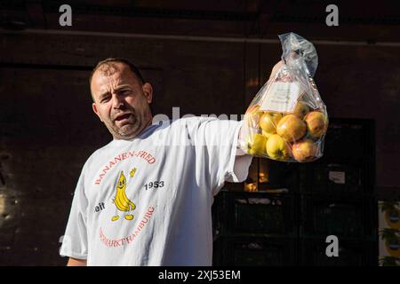 Bananen-Fred fruit vendor holding a plastic bag of apples at Fischtmarkt Sunday Market in Altona district of Hamburg, Germany Stock Photo