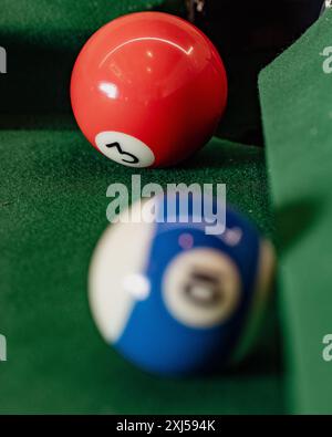 Macro shot of a billiards setup, focusing on the red and blue striped pool balls against the lush green backdrop, illustrating precision and strategy Stock Photo