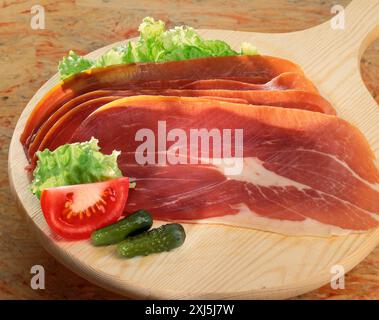 Slices of raw ham on a wooden board Stock Photo