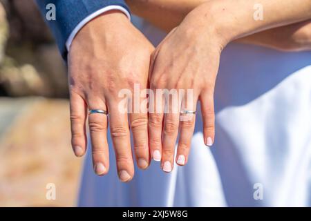 A couple is holding hands and wearing wedding rings. The man's ring is on the left hand and the woman's ring is on the right hand Stock Photo