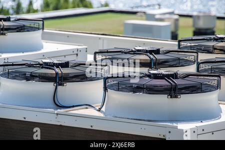 Close-up view of multiple commercial HVAC units on a building rooftop. These industrial air conditioning systems feature cooling fans and advanced tec Stock Photo