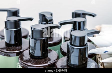 A close-up view of several black pump dispenser bottles, perfect for soap or lotion, adorned with water droplets on their surfaces, emphasizing a clea Stock Photo