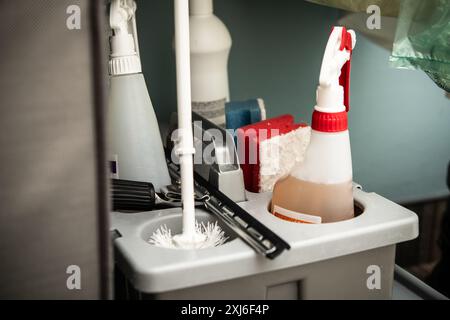Close-up view of a fully-equipped professional cleaning caddy, containing various cleaning supplies like spray bottles, sponges, and brushes against a Stock Photo