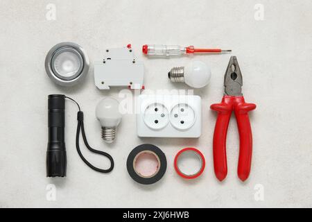 Set of electrician's tools, socket and light bulbs on white grunge background Stock Photo
