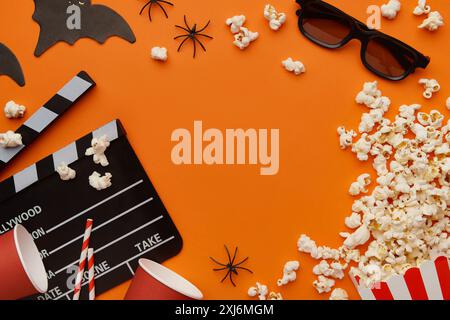 Popcorn, clapperboard, paper cup and halloween decor on a red background. Flat lay, copy space. Stock Photo