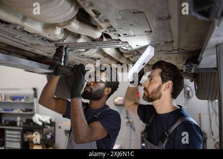 Two mechanics working under car in auto repair shop Stock Photo