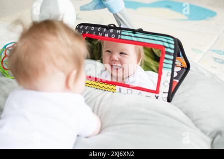 Baby looking at the mirror during tummy time. Infant emotional development Stock Photo