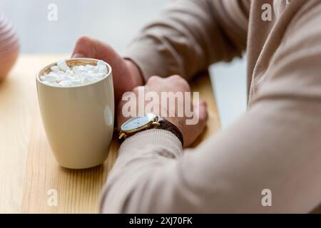 cropped image of man holding cup of coffee with marshmallow Stock Photo