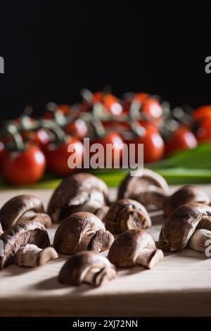 close-up shot of halved champignon mushrooms on wooden cutting board on black Stock Photo