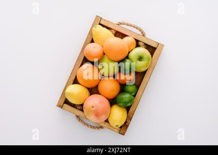 top view of various ripe fruits in wooden box on white tabletop Stock Photo