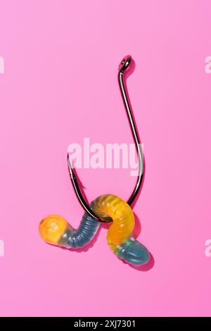 colorful gummy worm on fishing hook on pink Stock Photo