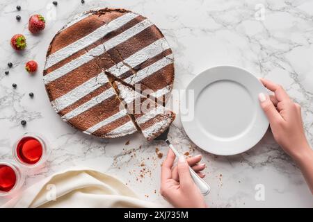 partial top view of person putting piece of delicious homemade cake on plate Stock Photo