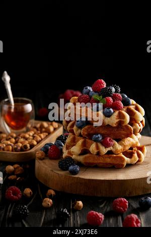 delicious belgian waffles with berries and hazelnuts on black wooden table Stock Photo