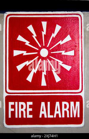 A graphic red and white fire alarm location sign at Sydney Observatory in Observatory Hill Park, Sydney, New South Wales, Australia. The sign depicts a graphical representation of sound waves emanating from a central point with the words Fire Alarm below. Stock Photo