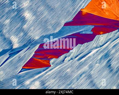 Polarised light micrograph of crystallised oxycodone (dihydrohydroxycodeinone). Oxycodone is an opioid medication and commonly prescribed for acute pain conditions but is also known for its high potential for dependency and misuse, leading to significant public health concerns related to opioid addiction. Crystalized and photographed in polarized light with retarders. Magnification: x140 when printed 10 centimetres wide. Stock Photo