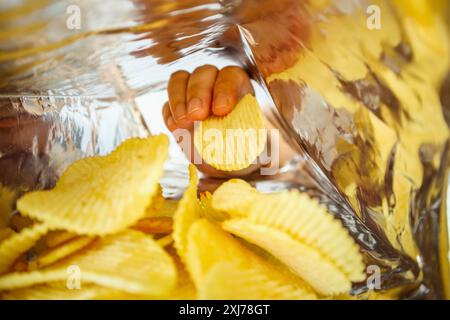 Hand hold potato chips inside snack foil bag Stock Photo