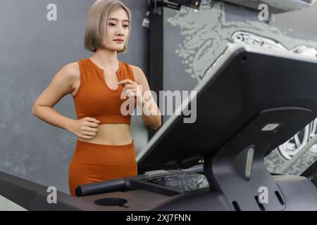 Young beautiful woman running on treadmill during her morning exercise at a gym Stock Photo