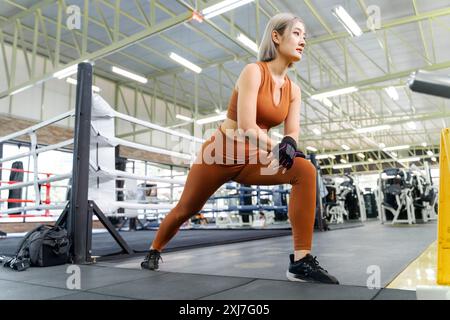 Young woman stretching her legs before starting her morning work out at a local gym Stock Photo