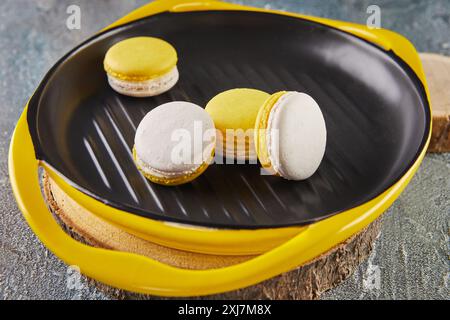 Colorful yellow and white macarons on a plate on a concrete background. Stock Photo