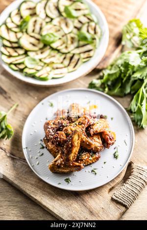 Grilled chicken wings on a plate and grilled zucchini as a side dish. Stock Photo