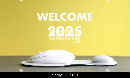 Welcome 2025, text on top of computer mouse and wrist pad. Stock Photo