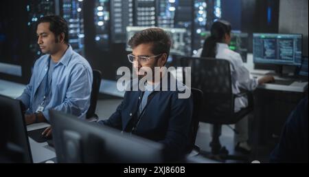 Portrait of a Handsome Indian Engineer Working on Desktop Computer in a Technological Office Environment. Research and Development Department Writing Software Code for an Innovative Internet Project Stock Photo