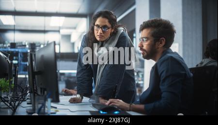 Two Diverse Multiethnic Indian Colleagues Having a Conversation While Busy Working on a Software Development Project. Engneer Talking with a Female Project Manager. Teamwork in Technology Laboratory Stock Photo