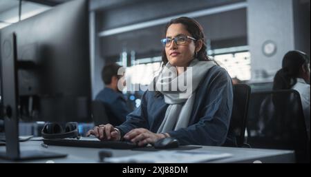 Portrait of a Thoughtful South Asian Engineer Working on Computer in a Technological Corporate Office. Young Woman Writing Software Code for an Innovative Internet and Software as a Service Project Stock Photo