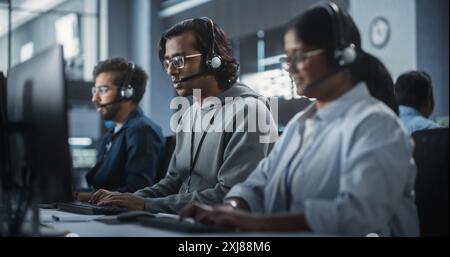 Indian Customer Support Team Using Computers and Talking with Clients Onlinel. Help Desk Employees Responds to Queries, Resolve Problems and Troubleshoot Issues, Implementing Solutions Stock Photo